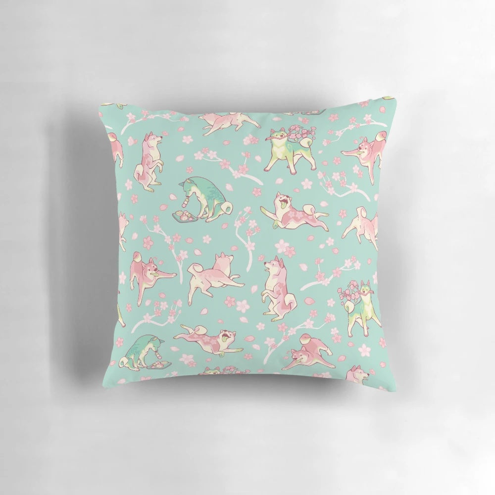 A beautiful mint green pillow featuring a design of a shiba inu dog surrounded by sakura blossoms and matcha leaves.