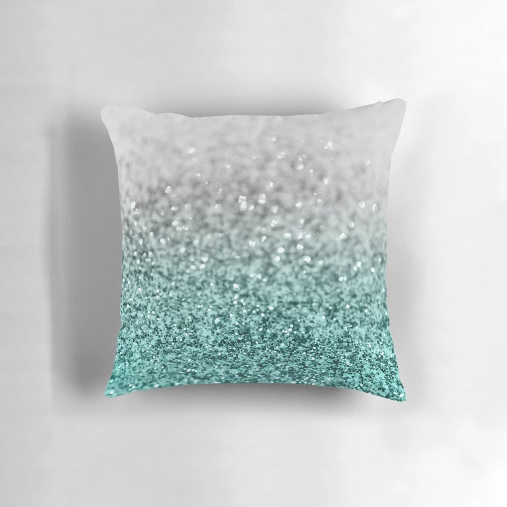 Closeup photo of a silver and teal pillow with a glittering, bokeh-like design, evoking a magical ocean scene.