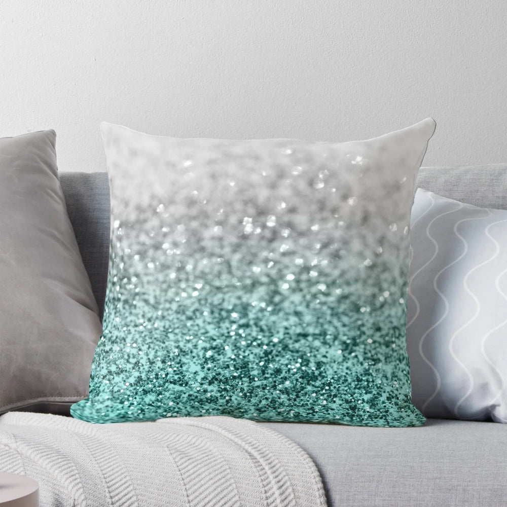 Closeup photo of a silver and teal pillow with a glittering, bokeh-like design, evoking a magical ocean scene.