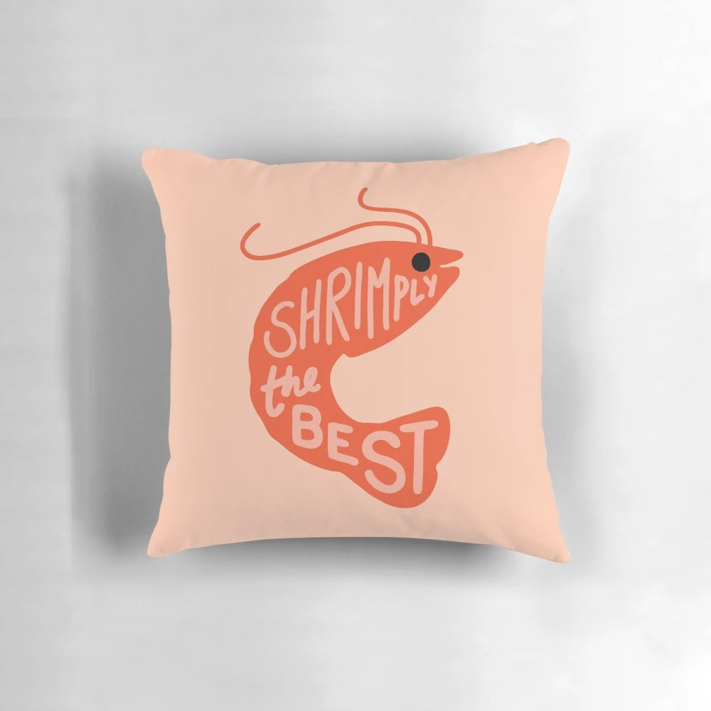 A red and pink cartoon shrimp pillow with the text "Shrimply the Best