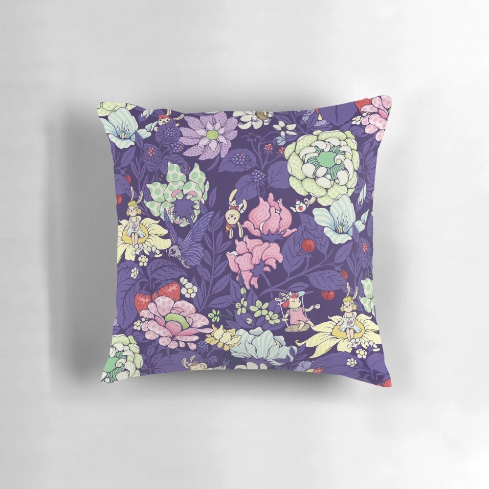 A plush, decorative pillow featuring a whimsical garden party design with bunnies, flowers, and blueberry tea.