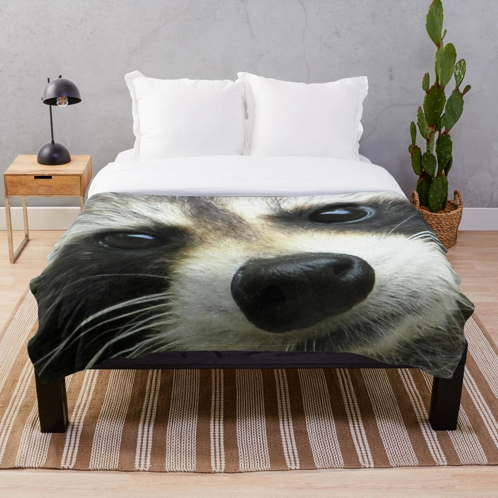 Soft and cozy plush blanket with a cute raccoon face design