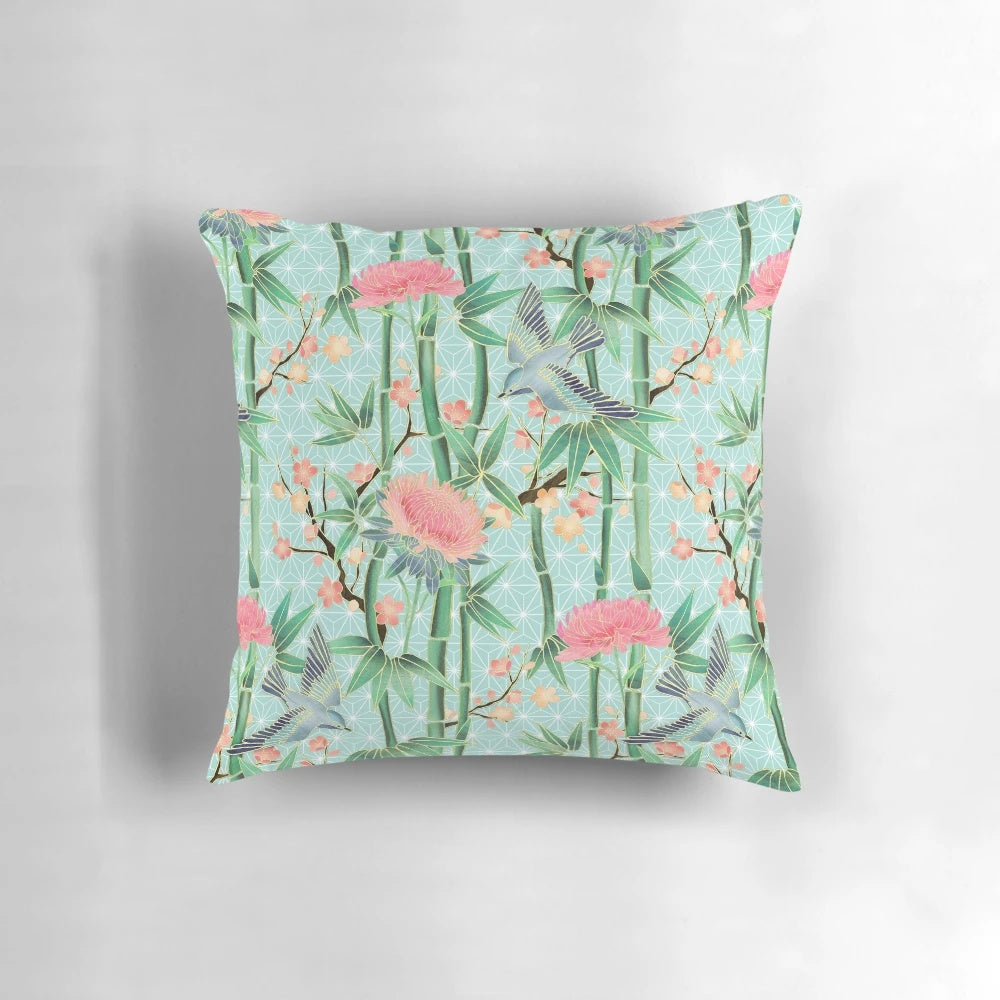 A soft, blue-green pillow featuring a Japanese-inspired pattern of bamboo, birds, and blossoms.