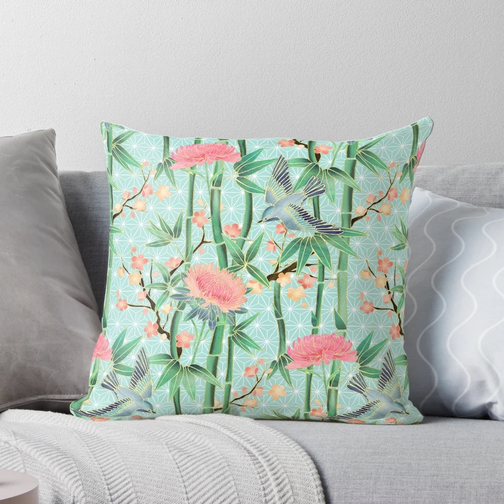 A soft, blue-green pillow featuring a Japanese-inspired pattern of bamboo, birds, and blossoms.