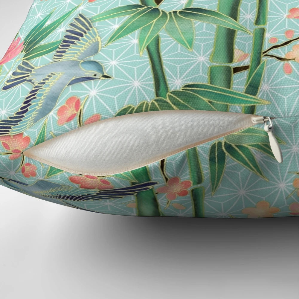 A soft, blue-green pillow featuring a Japanese-inspired pattern of bamboo, birds, and blossoms.