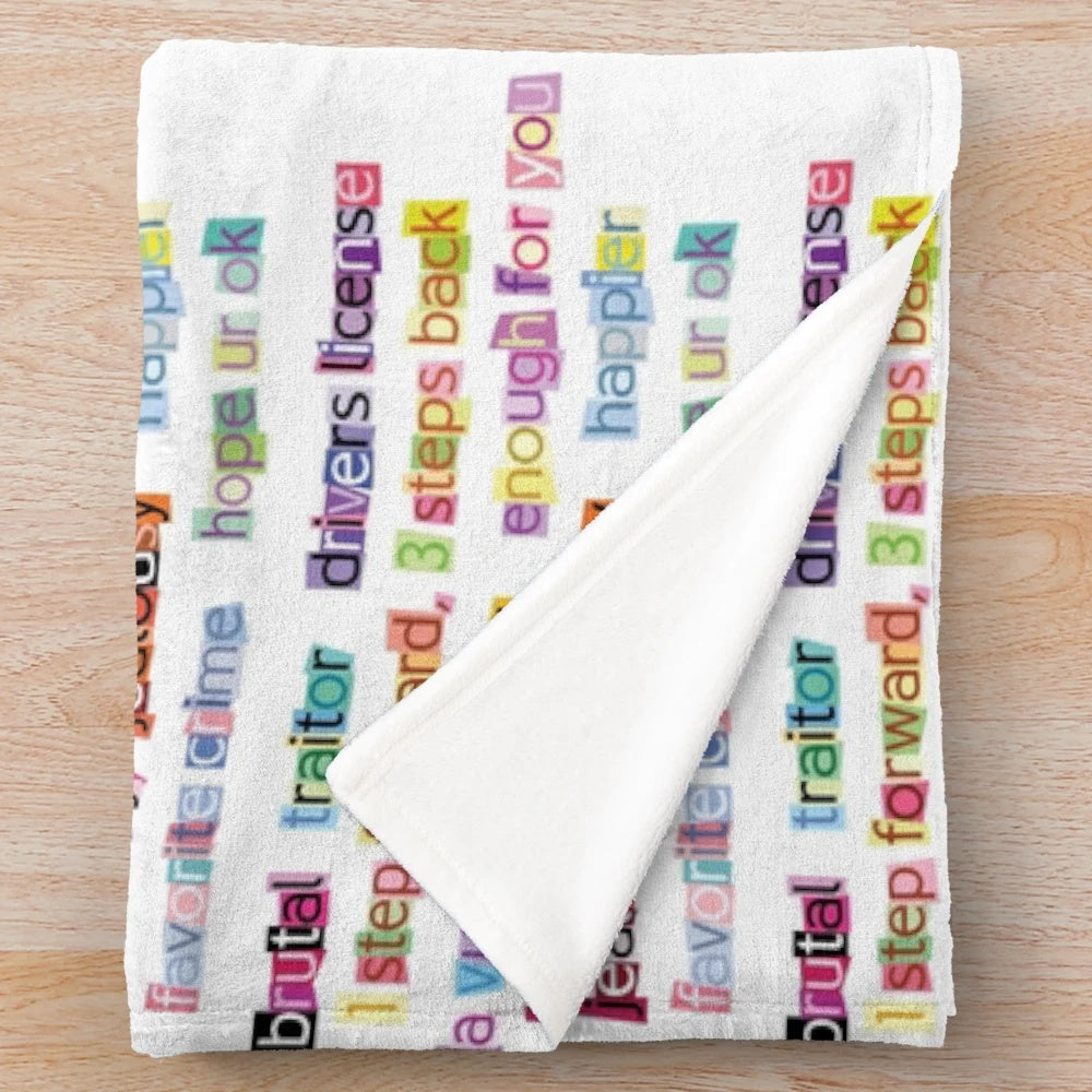 Soft plush blanket decorated with song titles from Olivia Rodrigo's album Sour