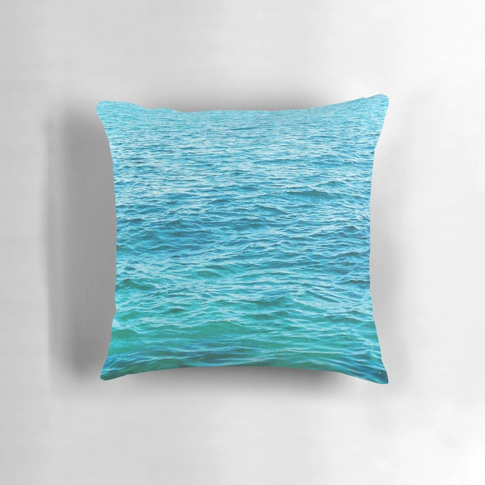 Vibrant turquoise ocean pillow with crashing waves, perfect for coastal-inspired home decor
