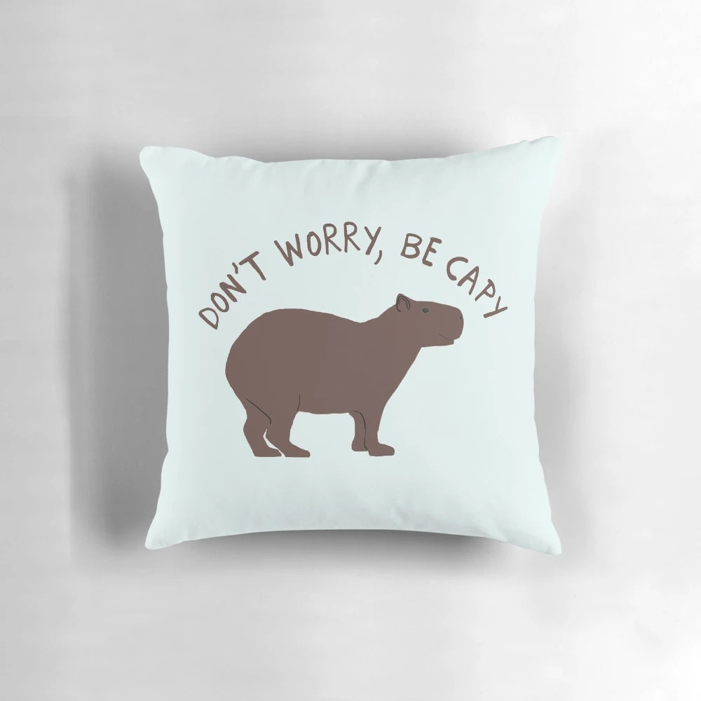 Capybara illustration on a soft, plush pillow with the text "Don't Worry, Be Capy