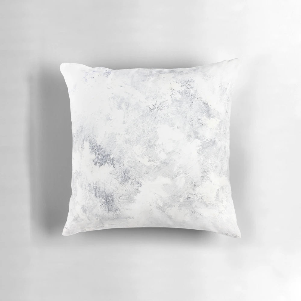 A serene white rabbit nestled in a captivating snowstorm, featured on a modern, minimalist pillow.