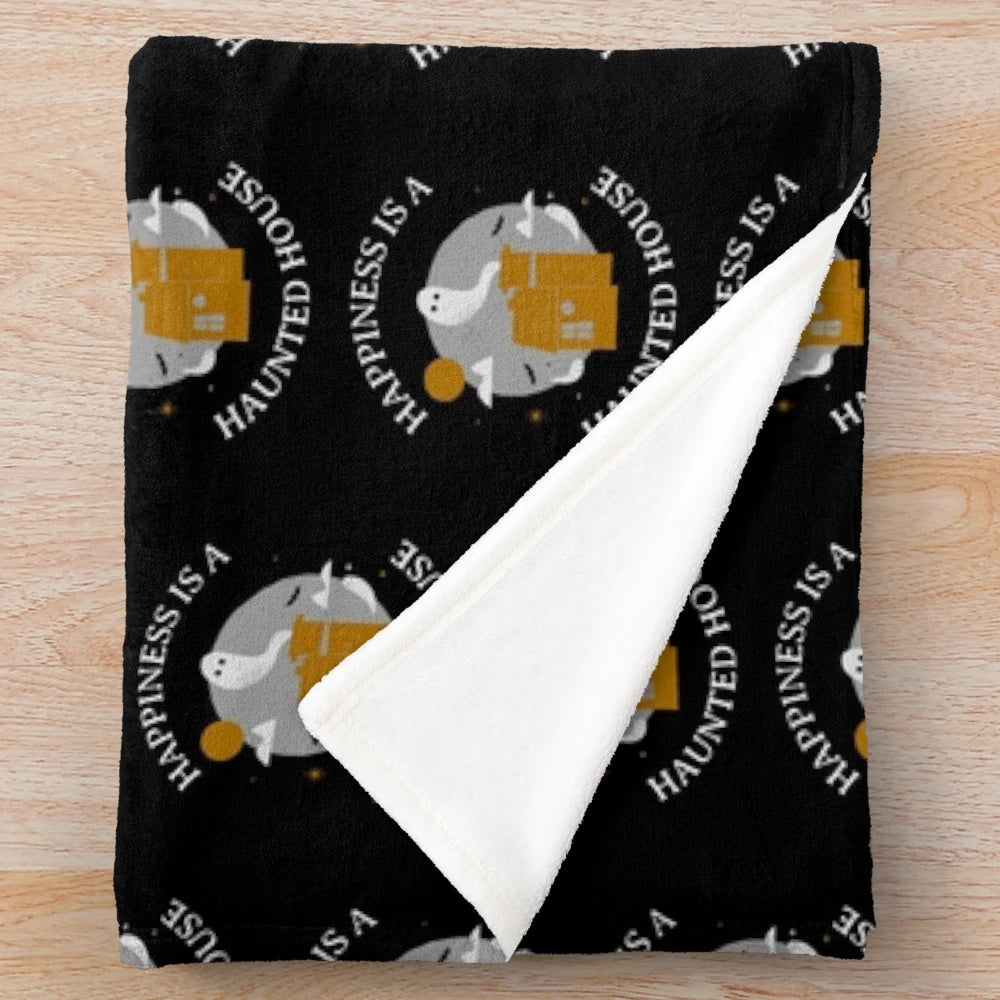 Haunted house plush blanket on a bed with pumpkins and autumn leaves