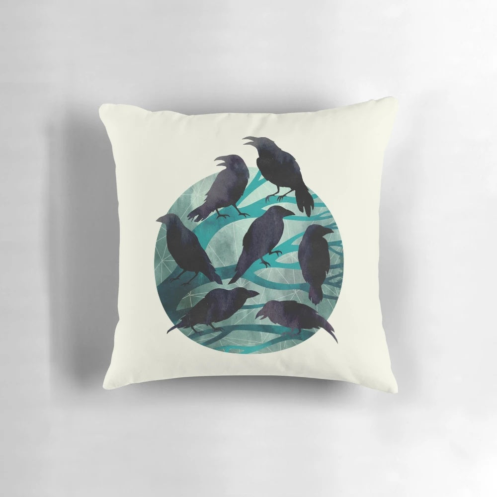 A decorative pillow featuring a watercolor illustration of a raven perched on a branch against a nighttime sky.