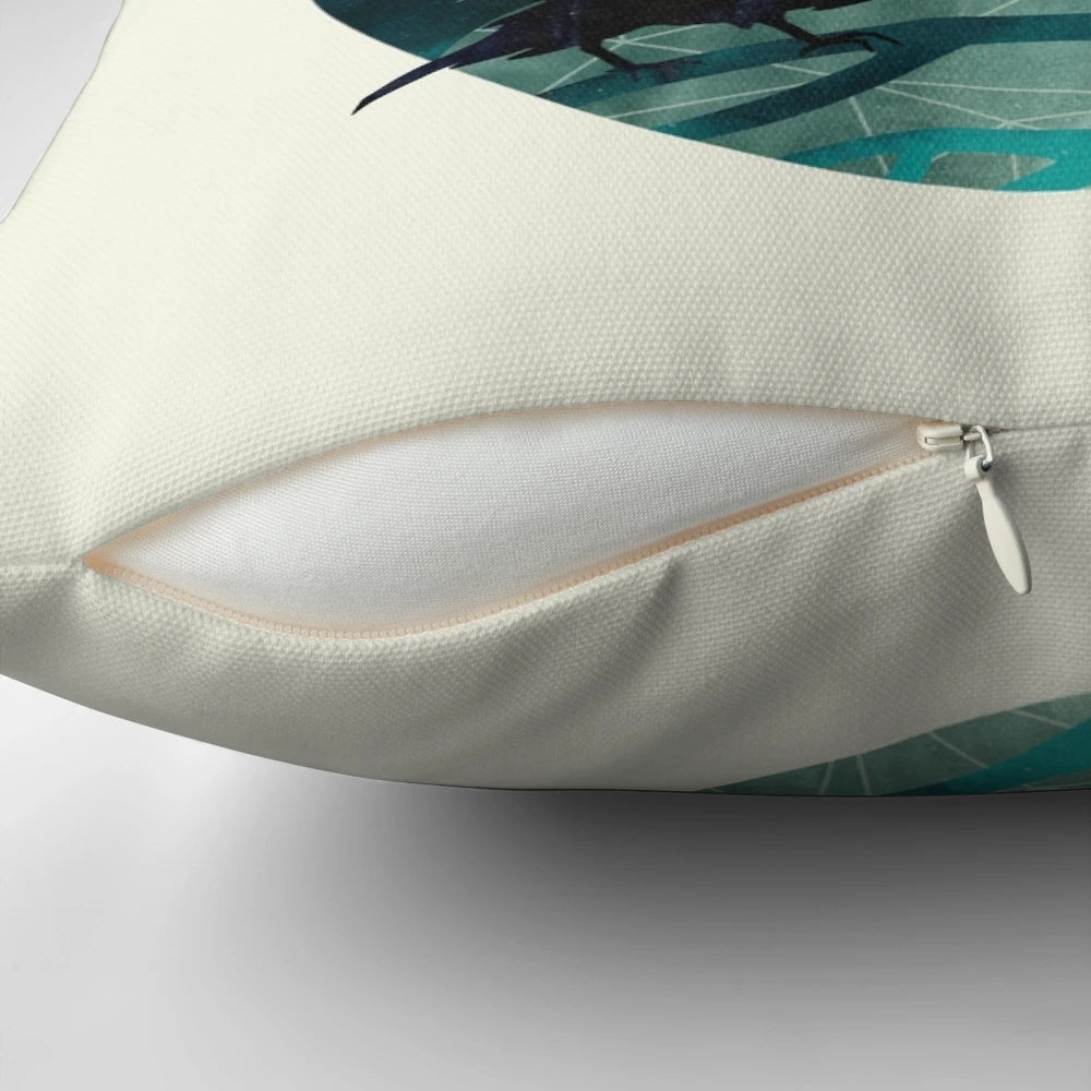 A decorative pillow featuring a watercolor illustration of a raven perched on a branch against a nighttime sky.