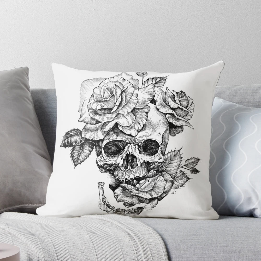 A black and white pen and ink drawing of a skull surrounded by roses on a decorative pillow.