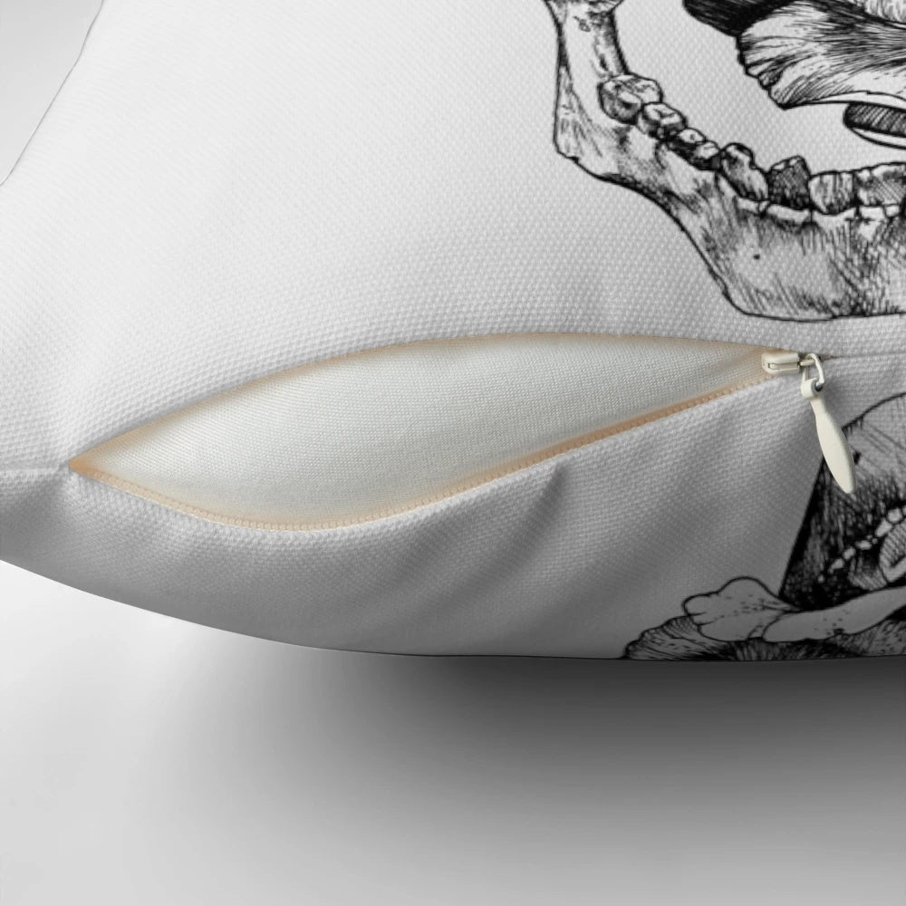 A black and white pen and ink drawing of a skull surrounded by roses on a decorative pillow.