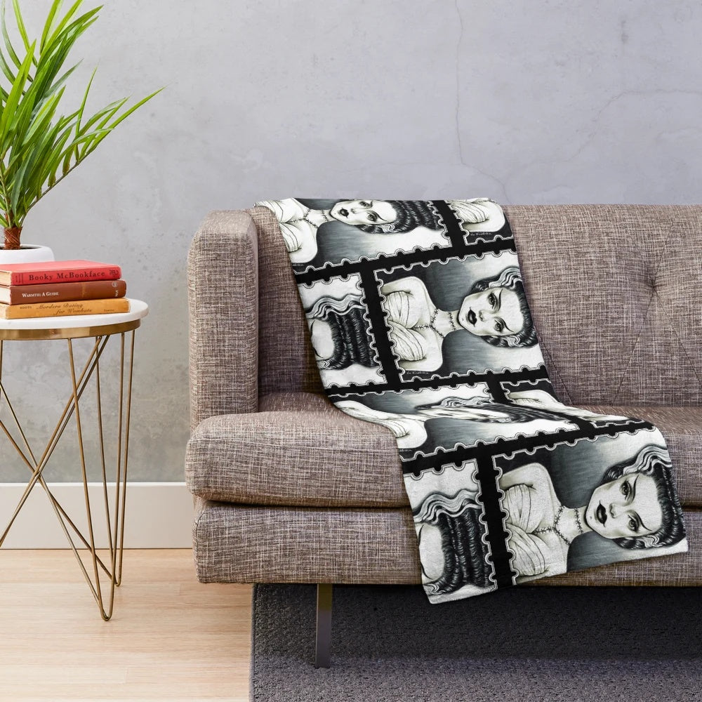 A plush blanket featuring a vintage-inspired black and white illustration of the Bride of Frankenstein character.