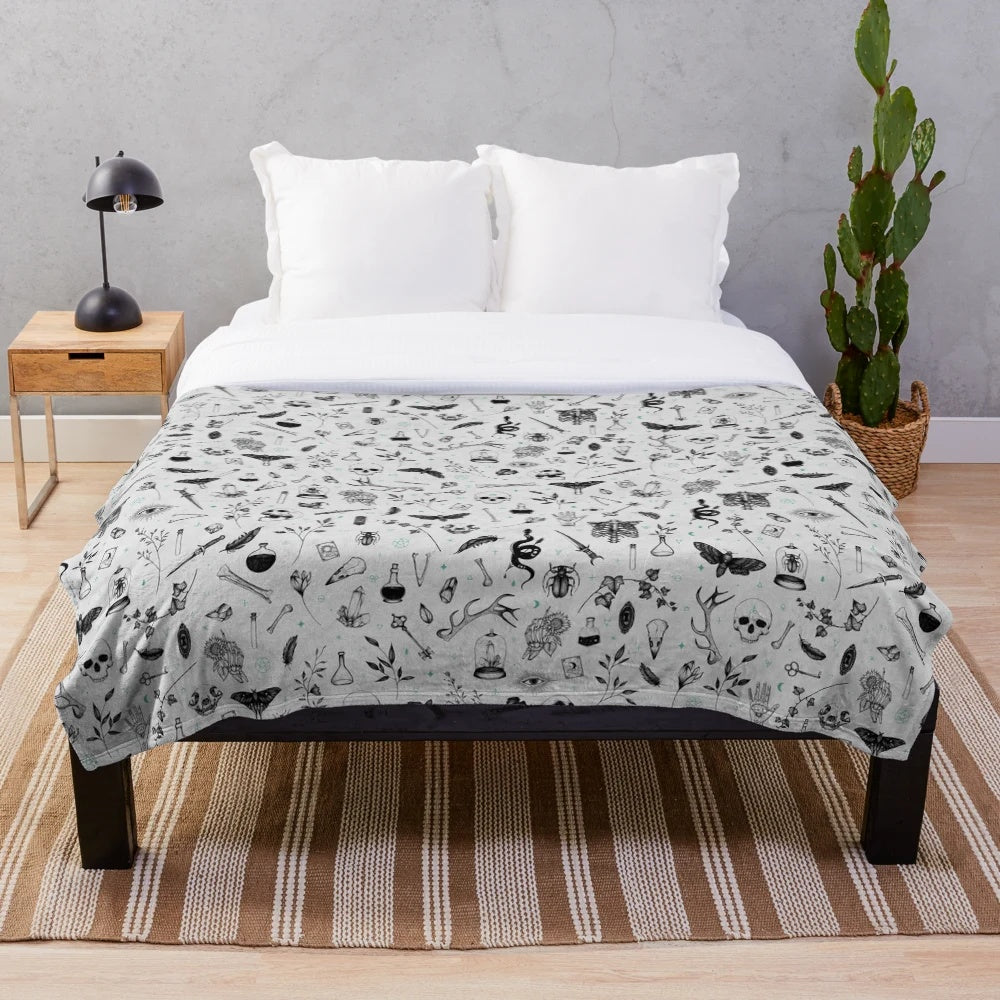 Plush blanket with a dark, witchy pattern featuring moons, stars, and skulls