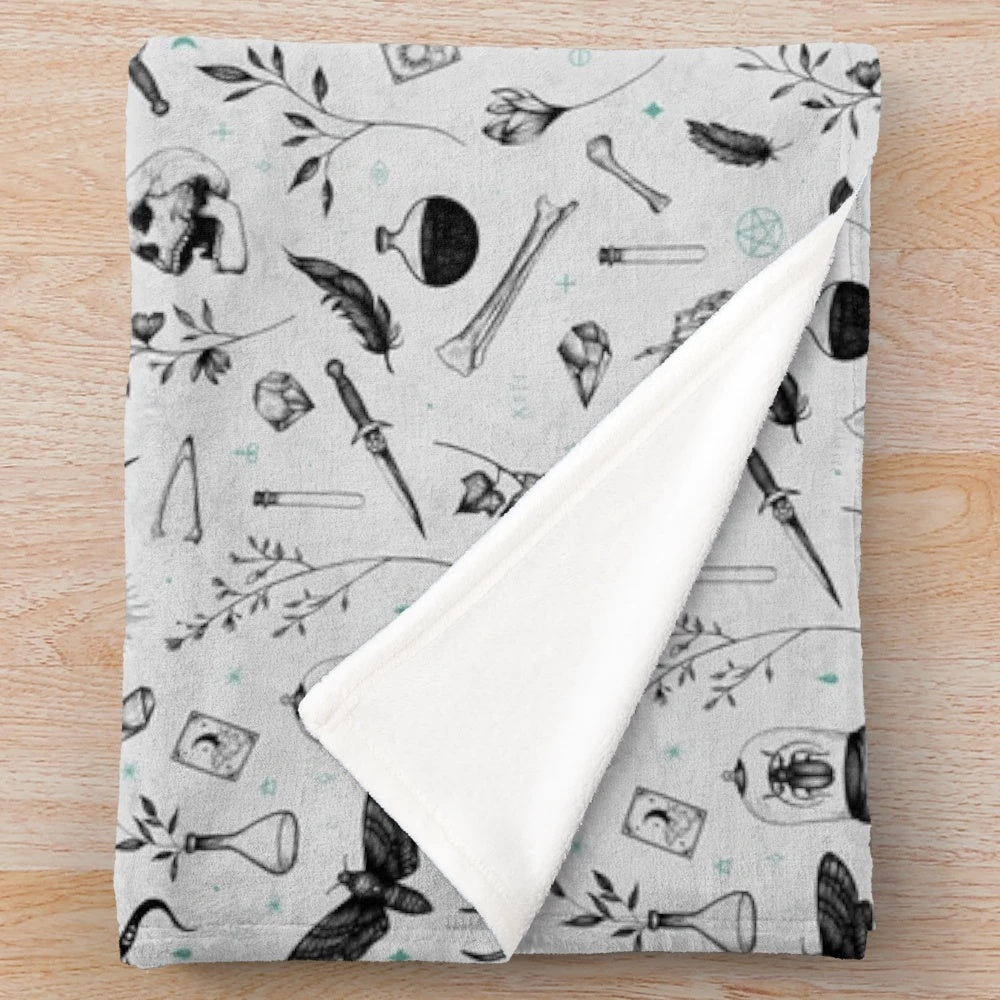 Plush blanket with a dark, witchy pattern featuring moons, stars, and skulls