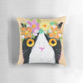 Tuxedo cat wearing a flower crown on a decorative pillow