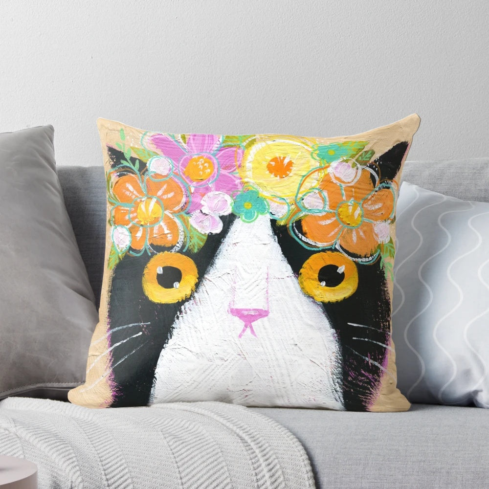 Tuxedo cat wearing a flower crown on a decorative pillow