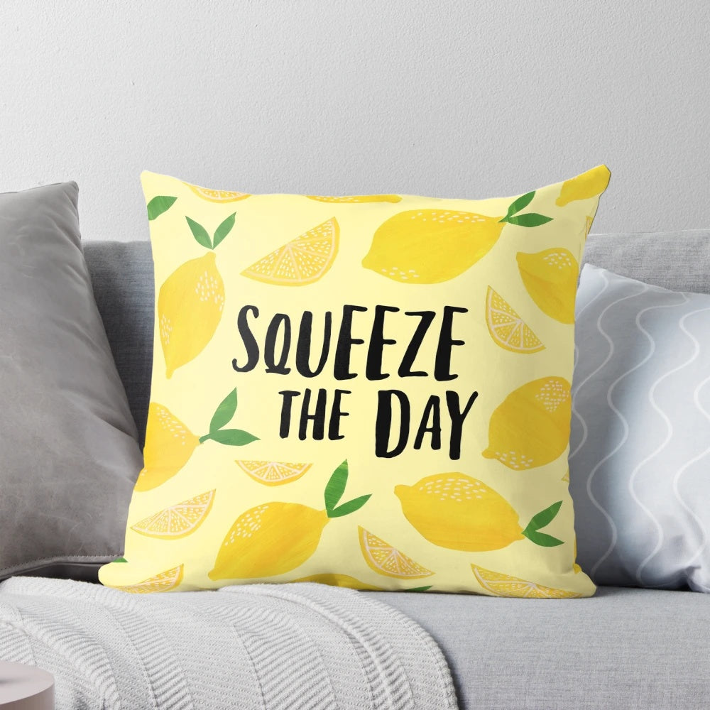 A plush, square pillow featuring a lemon design with the text "Squeeze the Day" as a motivational and humorous home or office decor accessory.