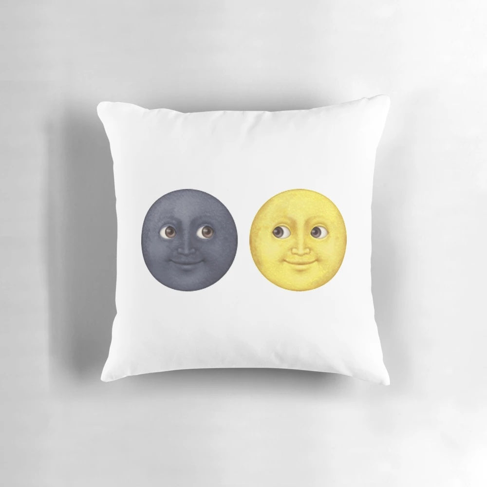 A decorative pillow featuring staring moon face emojis in yellow and dark colors.
