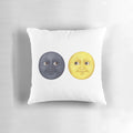 A decorative pillow featuring staring moon face emojis in yellow and dark colors.