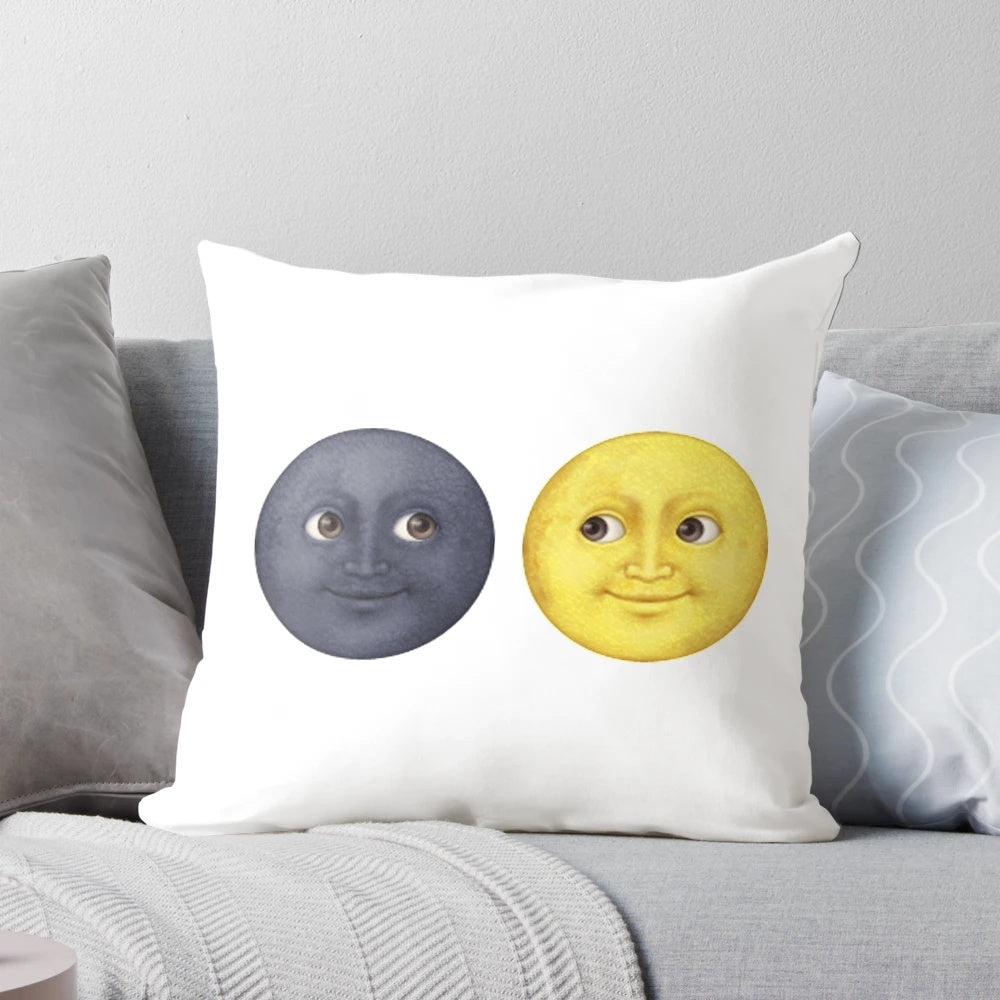 A decorative pillow featuring staring moon face emojis in yellow and dark colors.