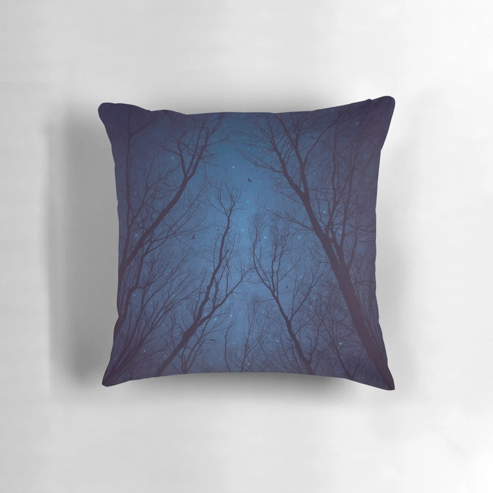 A decorative throw pillow featuring a print of a night sky with a silhouette of trees and a galaxy of stars in shades of indigo blue.