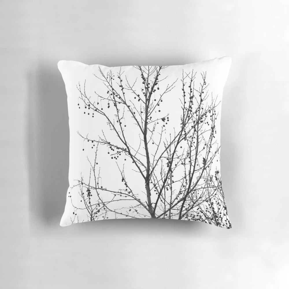 A decorative black and white pillow featuring an abstract design of bare tree branches against a neutral background, capturing the beauty of the autumn season.