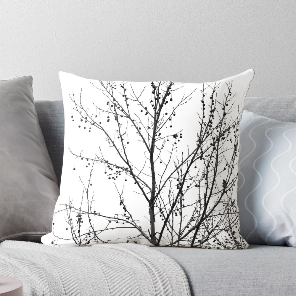 A decorative black and white pillow featuring an abstract design of bare tree branches against a neutral background, capturing the beauty of the autumn season.