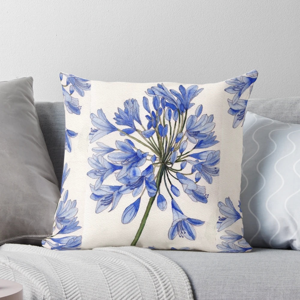 Vibrant watercolor painting of blue agapanthus flowers on a decorative pillow