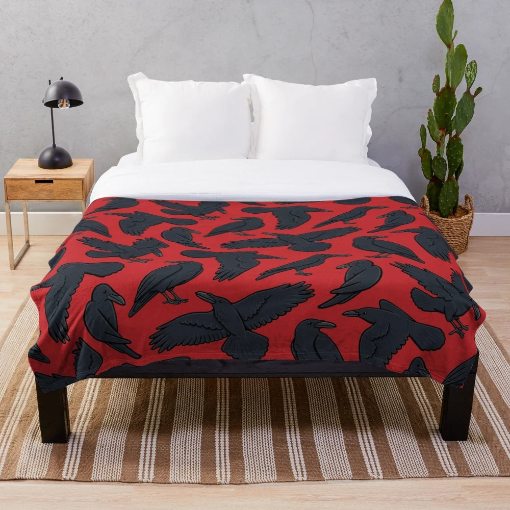A plush blanket featuring a repeating pattern of crows or ravens in black and red