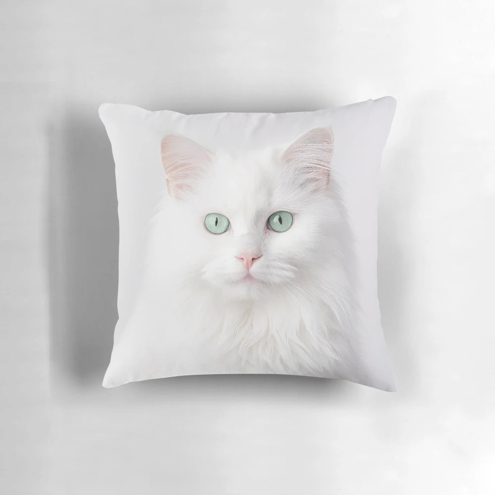 Soft, fluffy white Persian cat with vibrant green eyes on a decorative pillow