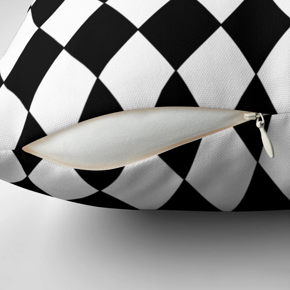 A black and white harlequin pattern pillow with a classic diamond design.