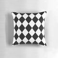 A black and white harlequin pattern throw pillow with a seamless diamond or lozenge shape design.