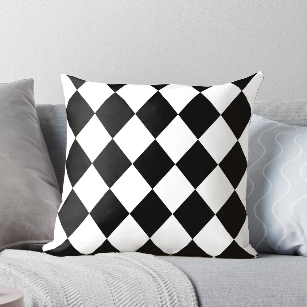 A black and white harlequin pattern throw pillow with a seamless diamond or lozenge shape design.