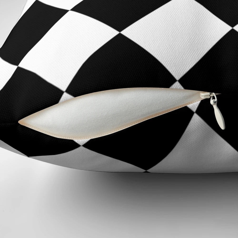 A black and white harlequin pattern throw pillow with a seamless diamond or lozenge shape design.