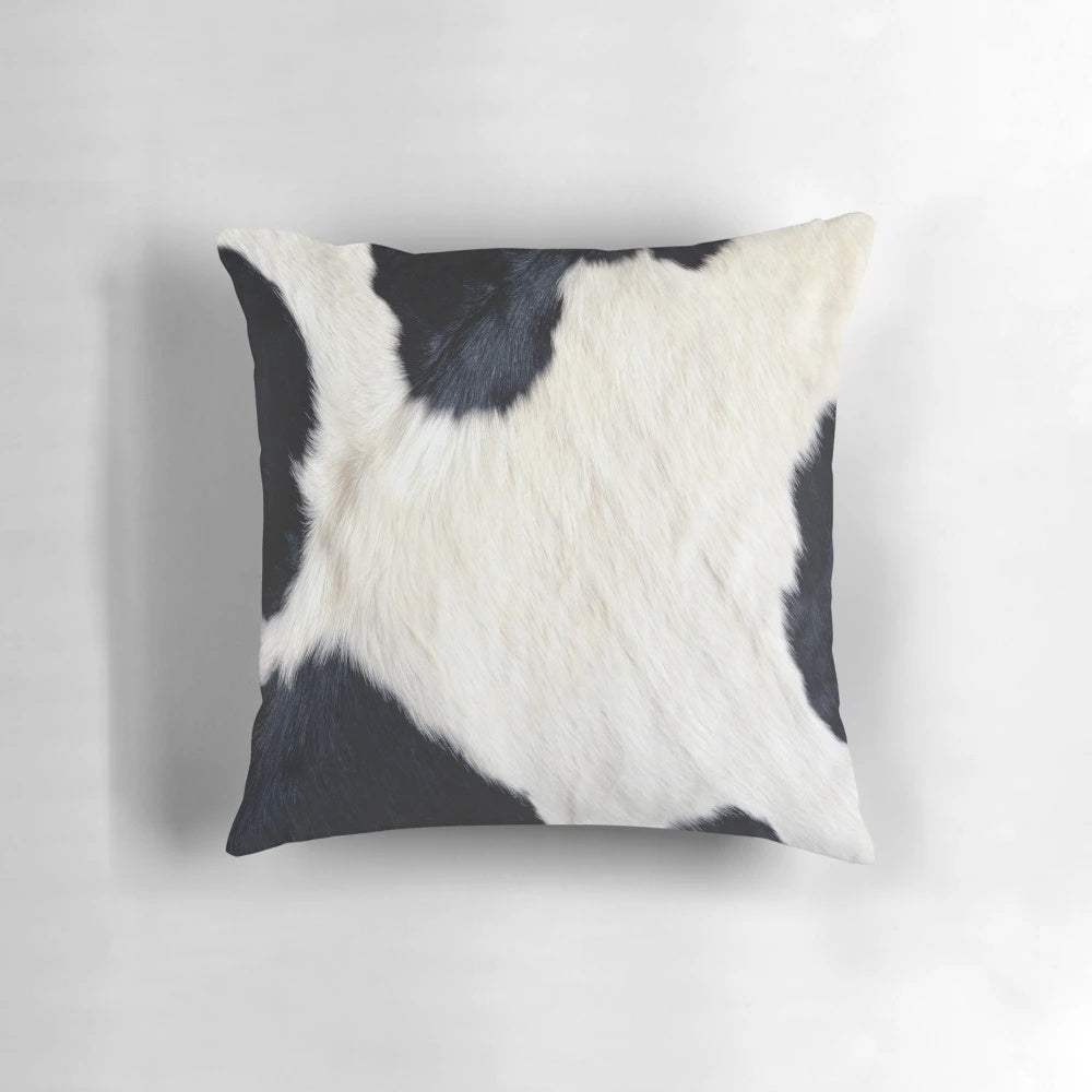 A black and white pillow with a faux cowhide pattern, creating a natural and textured look.