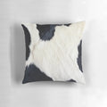 A black and white pillow with a faux cowhide pattern, creating a natural and textured look.