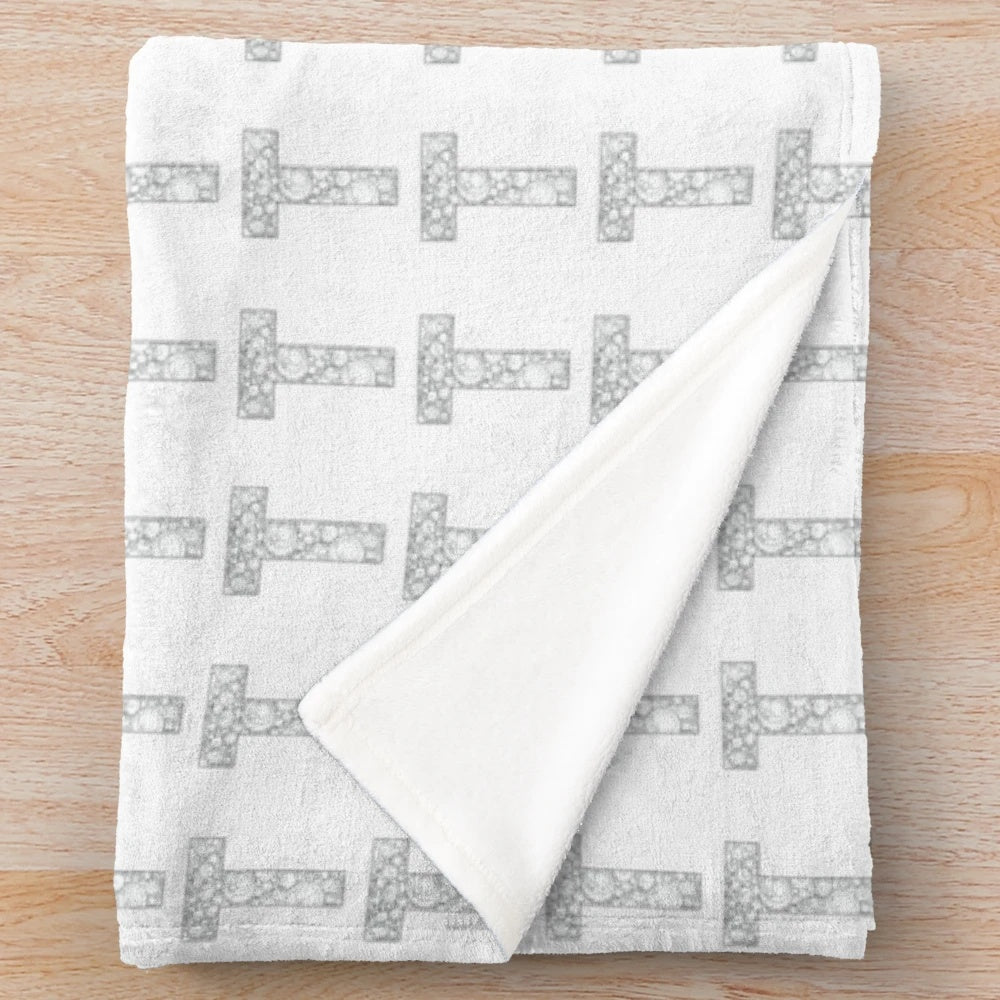 A cozy plush blanket featuring a bold, stylized letter T pattern in black and white