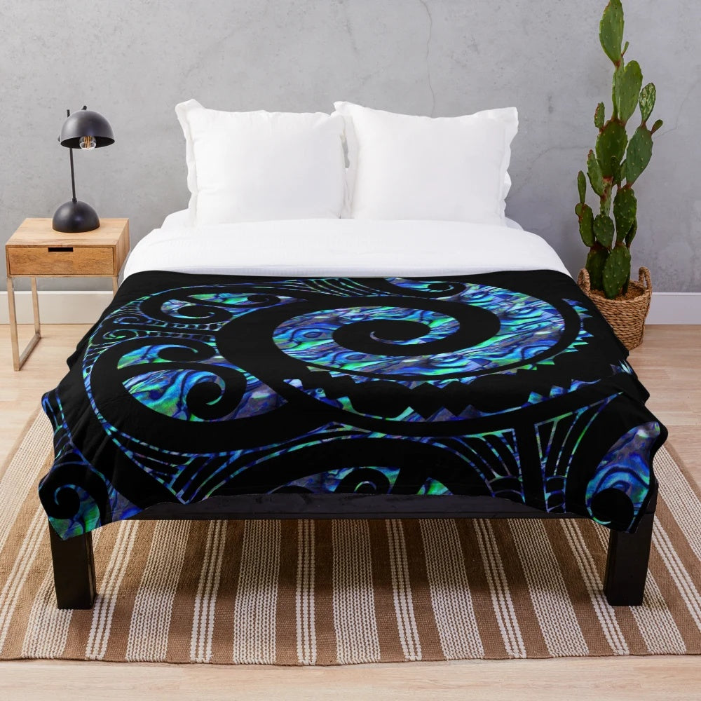 Plush blanket with a Maori-inspired paua tattoo koru design