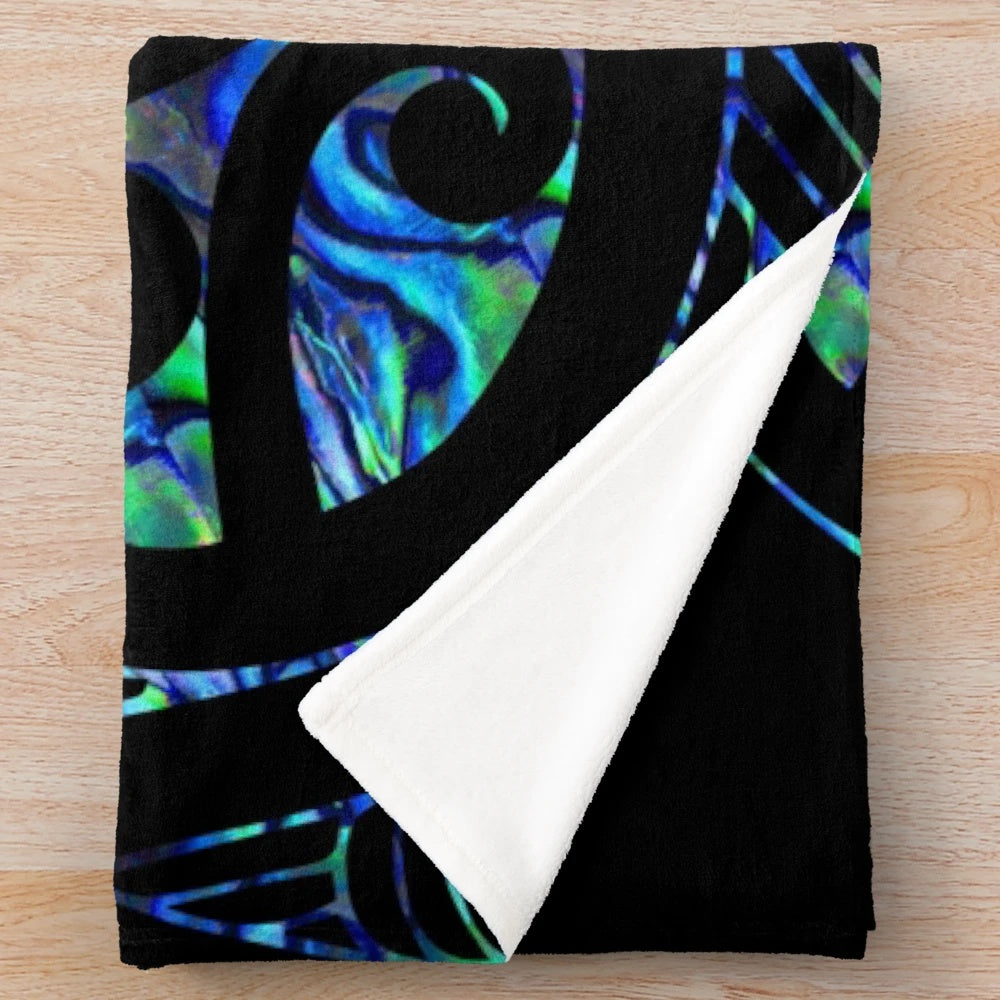 Plush blanket with a Maori-inspired paua tattoo koru design