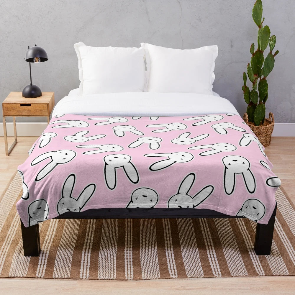Millennial pink plush blanket featuring the iconic cross-eyed rabbit design from Bad Bunny's Oasis logo
