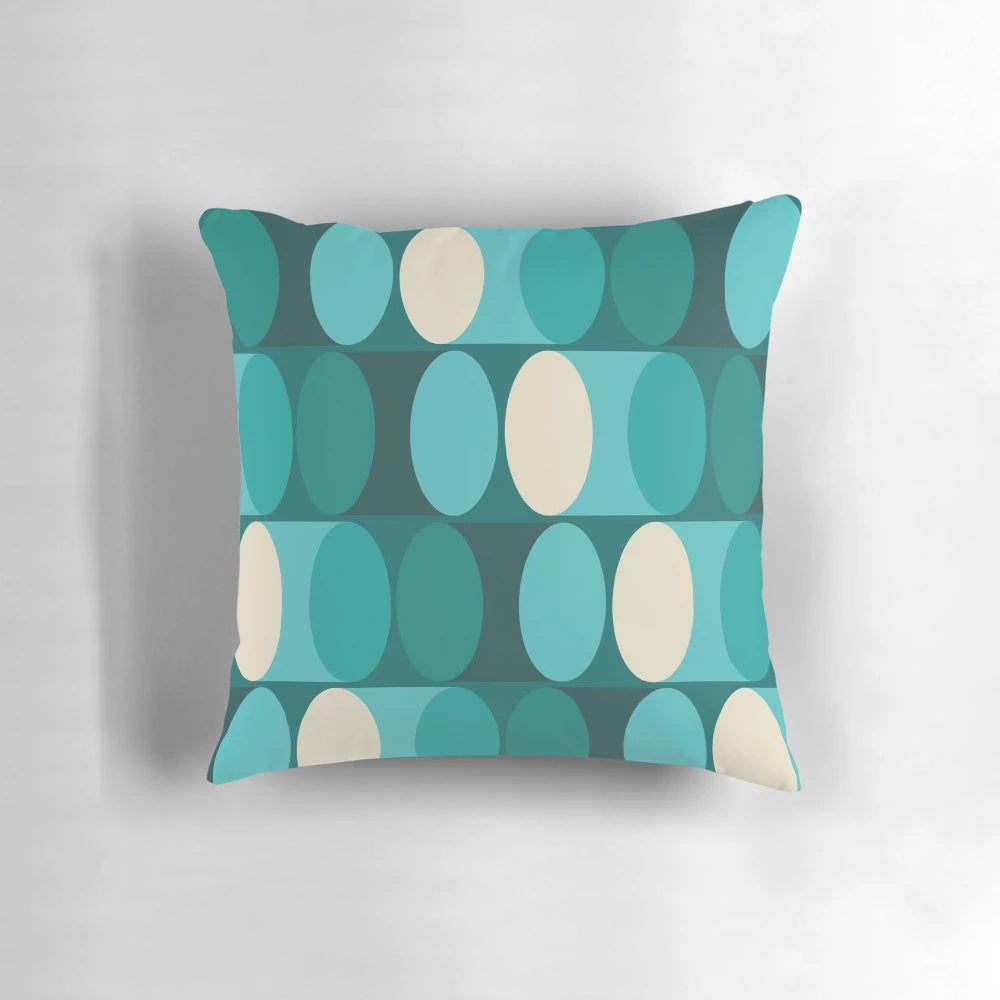 A bright, modern geometric pillow in shades of teal, green, and cream.