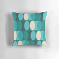A bright, modern geometric pillow in shades of teal, green, and cream.