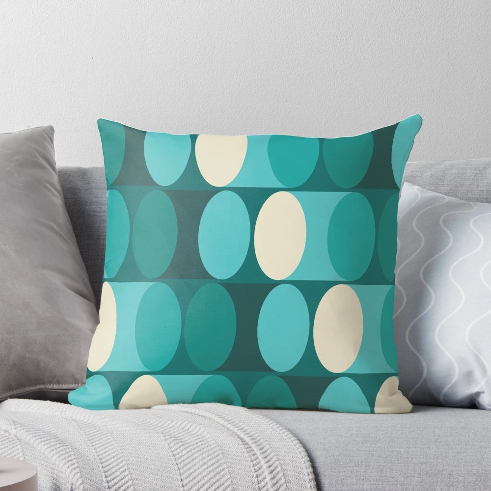 A bright, modern geometric pillow in shades of teal, green, and cream.