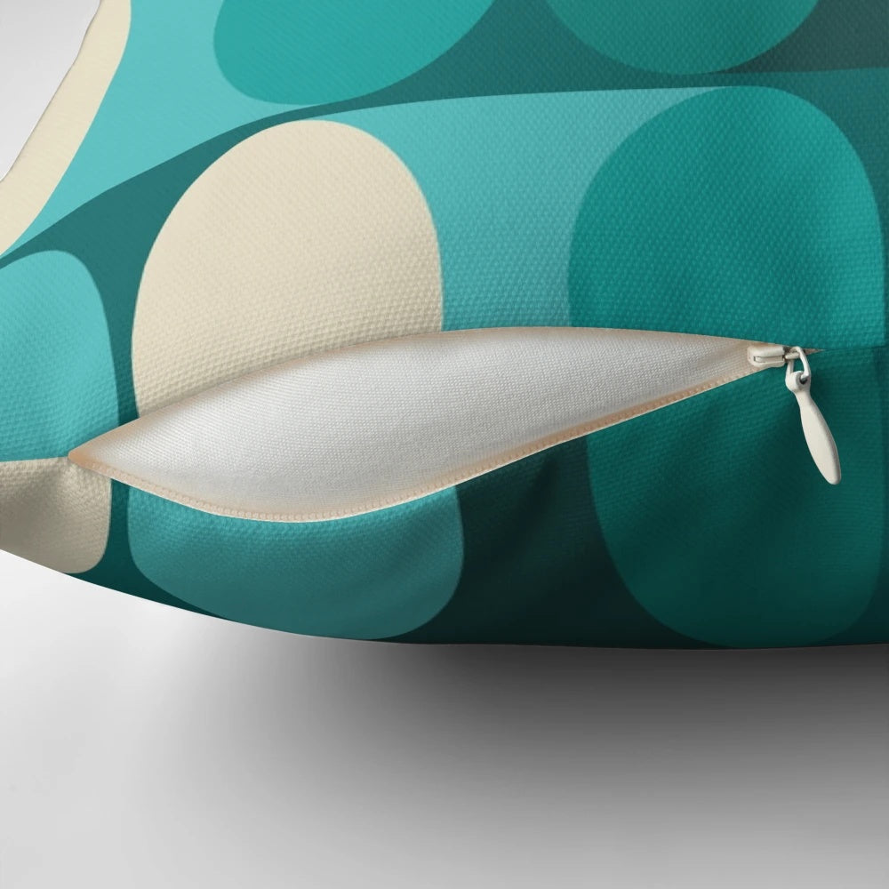 A bright, modern geometric pillow in shades of teal, green, and cream.