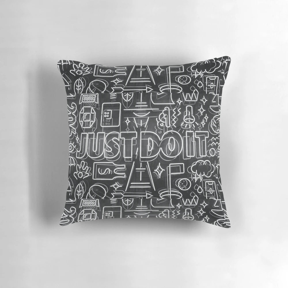 A white and black pillow featuring the iconic Nike "Just Do It" slogan in a cartoon-style design, perfect for adding motivation and style to any room.