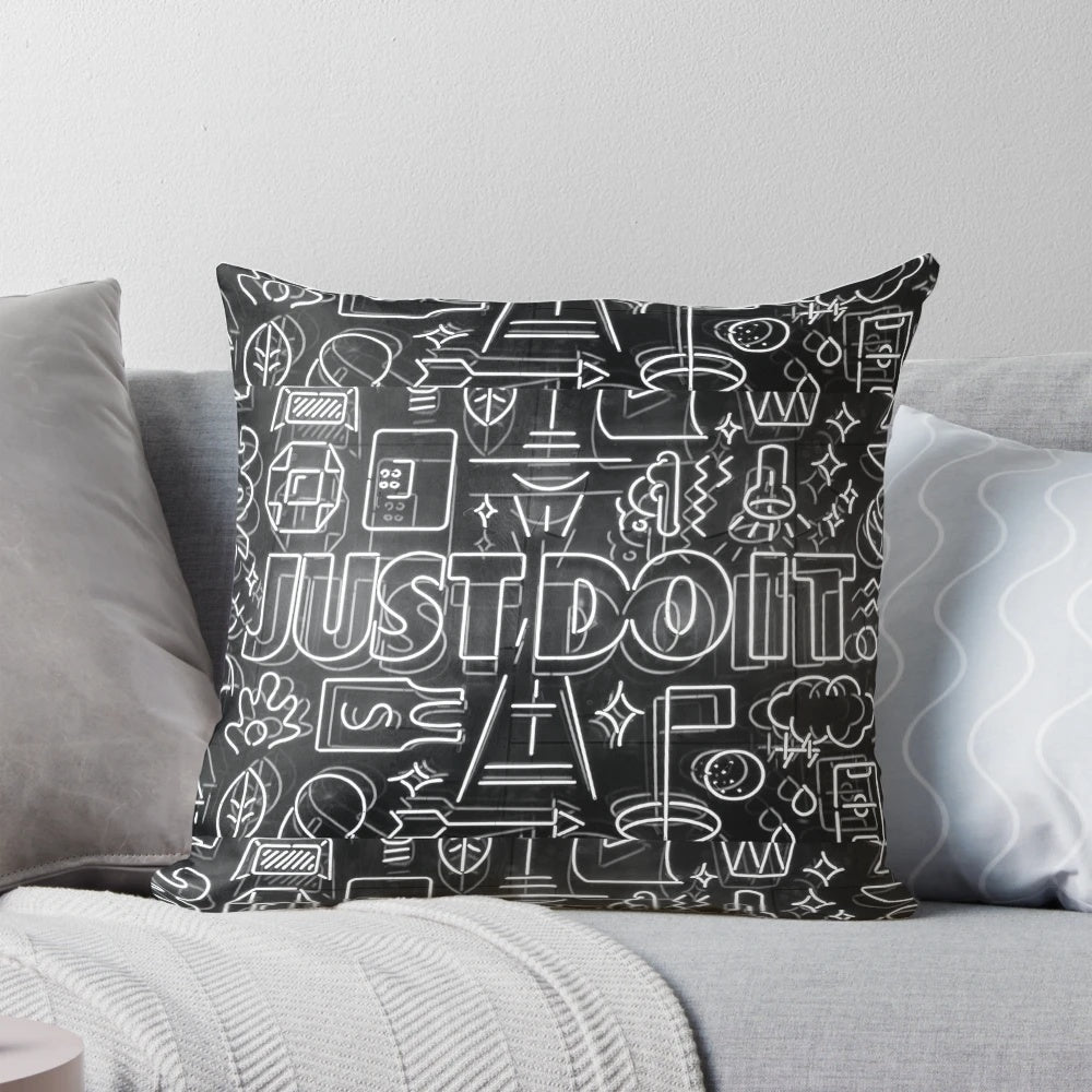 A white and black pillow featuring the iconic Nike "Just Do It" slogan in a cartoon-style design, perfect for adding motivation and style to any room.