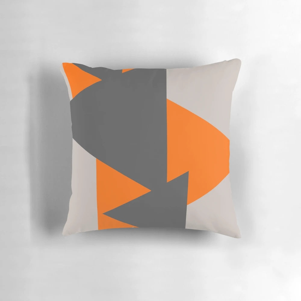 Close-up of a decorative throw pillow featuring a modern, minimalist pattern of orange and grey triangles.